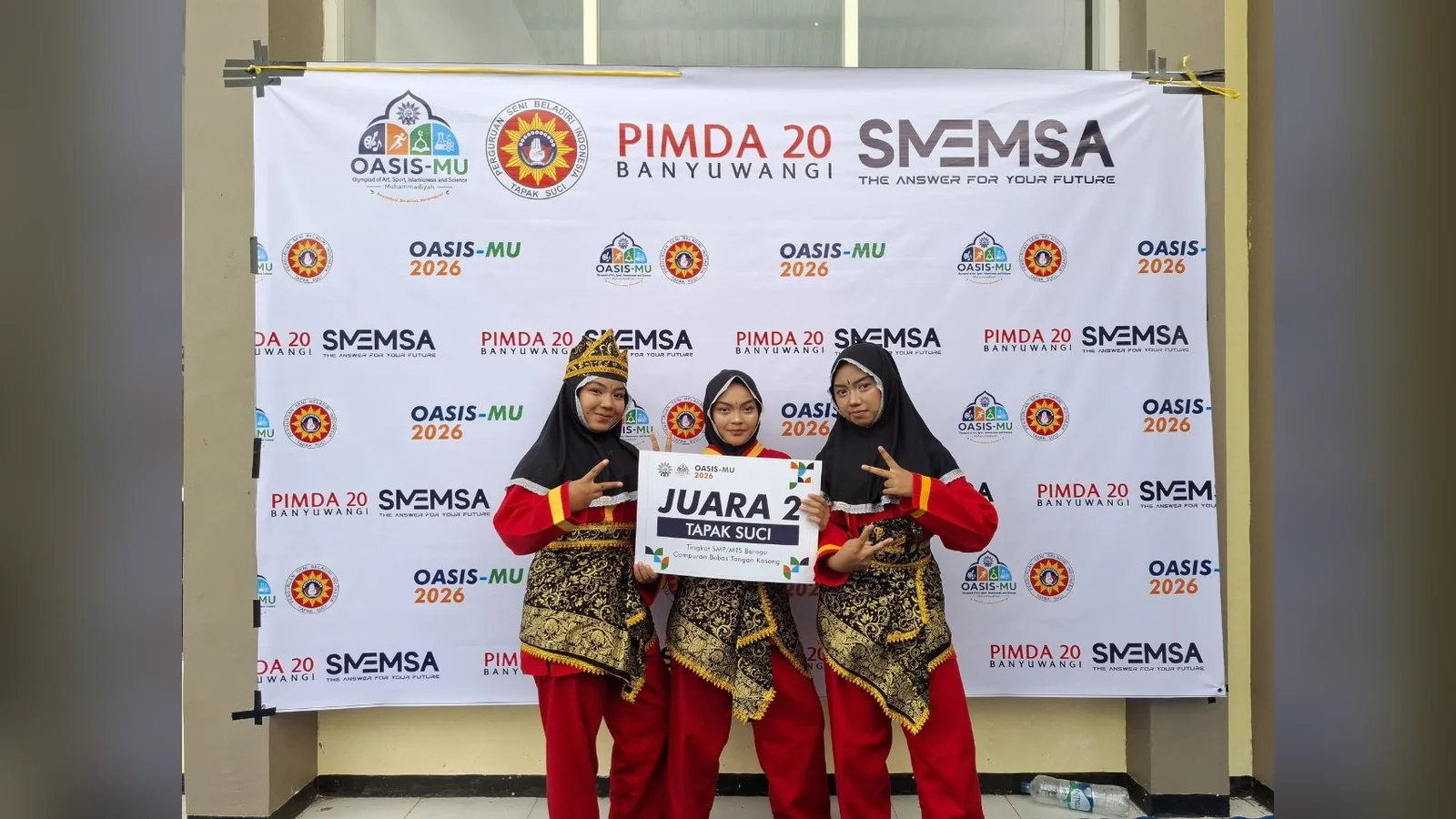 Foto Safira, Mikayla, dan Azzahra memegang plakat juara 2 seni beregu putri Tapak Suci OASISMU Banyuwangi 2026